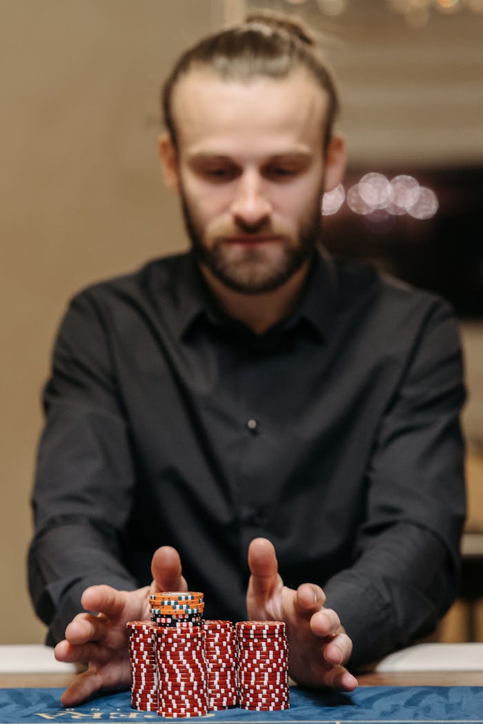 Focused man handling a stack of poker chips at a casino table, symbolizing gambling and risk.